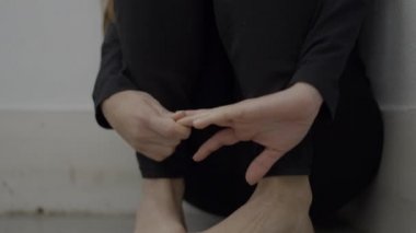 Close-up of young frightened woman sitting in corner of room, tilt up - 4K Horizontal video