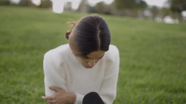 Занепокоєна Молода Жінка Сидить Траві Подряпає Руку Дивиться Вниз Горизонтальне — стокове відео