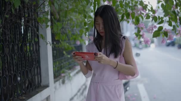 Дівчина Рожевій Сукні Збирається Вулиці Граючи Гру Своєму Мобільному Горизонтальне — стокове відео