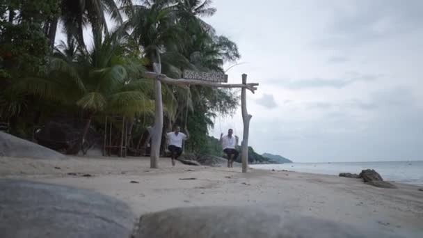 Caucasian Male Gay Couple Swinging Swing Beach Tropical Palms Koh — Stockvideo