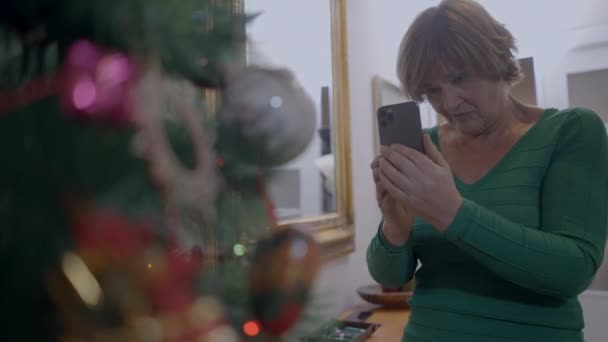 西班牙老妇人在家用智能手机相机为圣诞树装饰拍照 中型射击 水平4K视频 — 图库视频影像