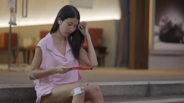 Girl Playing Games Her Smartphone Wearing Headphones Fixing Her Hair — Vídeo de Stock