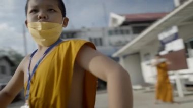 Bangkok sokaklarında eğlenen genç keşiş çocuklar solunum maskesi takıyorlar - 4K Yatay Video