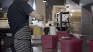 Kafkasyalı erkek aşçı restoran mutfağında çalışıyor. Vücut manzarası yarı açık. 4K yatay görüntü.