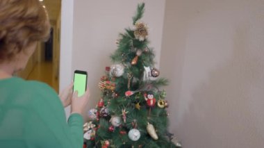 Yaşlı kadın süslenmiş Noel ağacının videosunu çekiyor. Orta Çekim - Yatay 4K video