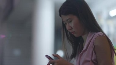 A lady sitting in airport and checking the news feed on her phone - 4K Horizontal video