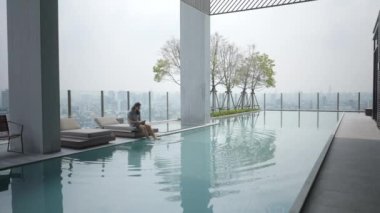 Bangkok, Tayland 'da bir otelin havuzunun yanındaki cep telefonunu kullanan uzun saçlı adam. Geniş açı - 4K yatay video