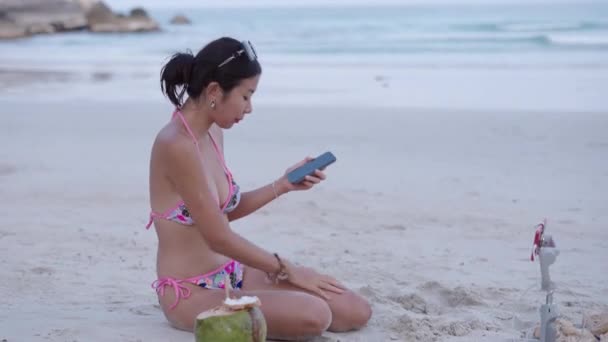 Азиатский Тайский Стример Записывающий Livestream Смартфона Сидя Бикини Песчаном Пляже — стоковое видео