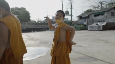Bangkok kırsalındaki bir meydanda dans eden neşeli genç keşiş - 4K Yatay video
