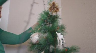 İspanyol Emekli Kadın Noel ağacının etrafına ip lambaları diziyor. Kapat - Yatay 4K videosu