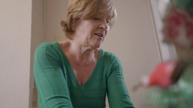 Yaşlı bir dul İspanyol kadın tatil sezonu için bir Noel ağacı hazırlıyor. Kapat - Yatay 4K videosu