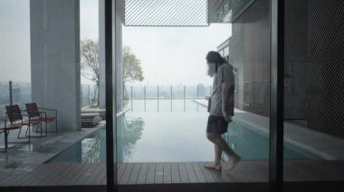 Bangkok, Tayland 'da havuz başında havuz başında yürüyen uzun saçlı bir adam. Statik Çekim - 4K Yatay Görüntü