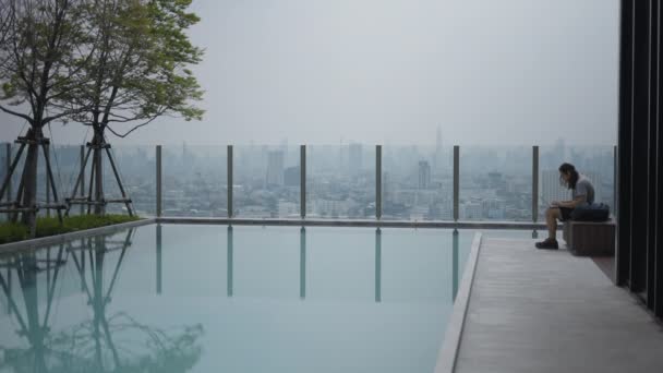 Tipo Está Utilizando Ordenador Portátil Sentado Salón Junto Piscina Edificio — Vídeo de stock