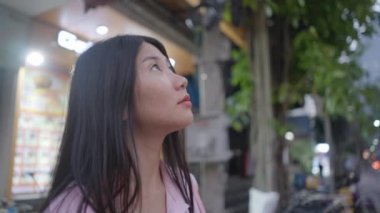 Kız gece gökyüzüne bakıp yıldızları saymış ve onlara doğru el sallamış. 4K Yatay video.