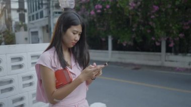 Kız dışarıda oturuyor ve akıllı telefon kullanıyor - 4K Yatay Video