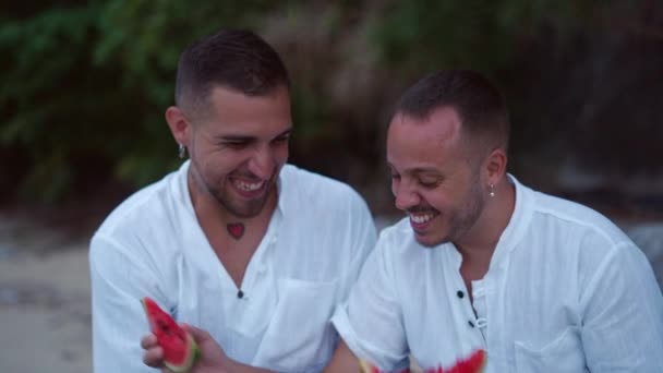 Diverse Gay Male Couple Eating Watermelon Together Talking Sitting Rocky — ストック動画