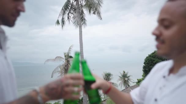 Male Gay Couple Clinking Bottles Beer Smiling While Resting Tropical — Stock Video