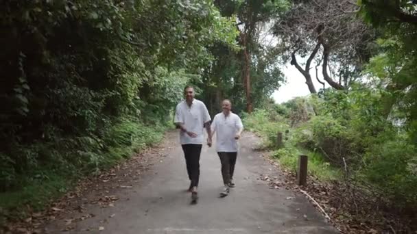 Male Gay Couple Walking Island Walkway Trail Holding Hands Showing — Vídeos de Stock