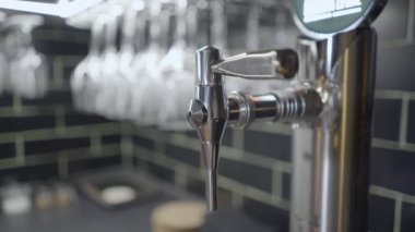 Close-up pan of metal tap for Estrella Galicia beer by glasses in bar - 4K Horizontal video