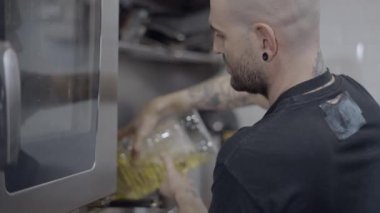 Side view of male chef pouring food oil into pot in restaurant kitchen - 4K Horizontal video