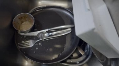 Close handheld push-out of dirty dishes in metallic kitchen sink - 4K Horizontal video