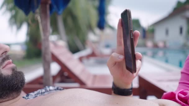 Bearded Man Scrolling Mobile Phone Screen While Lying Deckchair Swimming — 图库视频影像