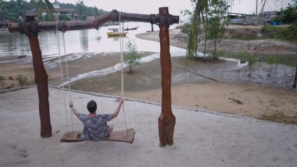 Задний Вид Взрослого Мужчину Качающегося Пляже Качелях Моря Деревне Таиланда — стоковое видео