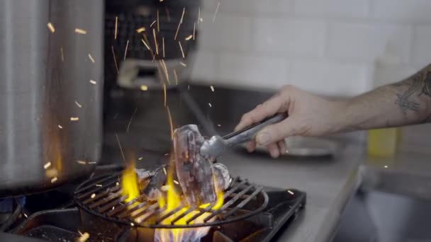 Slomo of sparks flying as chef moves charcoal on grill grate on stove - 4K Horizontal video