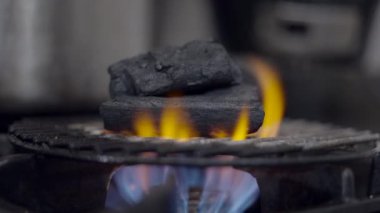 Close-up of flaming charcoal on grill grate on gas stove in kitchen - 4K Horizontal video