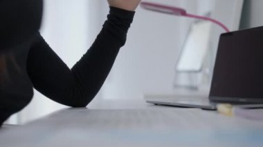 Close up shot of an unrecognizable young girls hands who is sitting at a desk and writing in her paper. - 4K Horizontal video