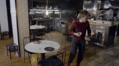 Kısa saçlı kadın boş restoranda tabak ve bardakları taşıyor - 4K Yatay video