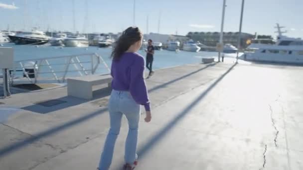 Lone Dark Haired Girl Roller Skates Sunlight Boats Harbor Horizontal — Video Stock
