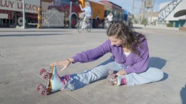 Renkli elbiseli ve patenci kız bacaklarını yere uzatıyor - 4K Yatay video