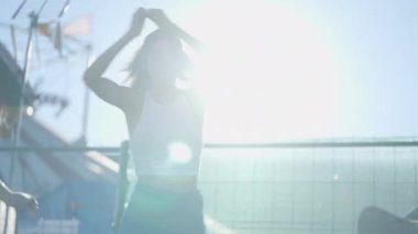 Close view of girl spinning around on roller skates in bright sunshine - 4K Horizontal video
