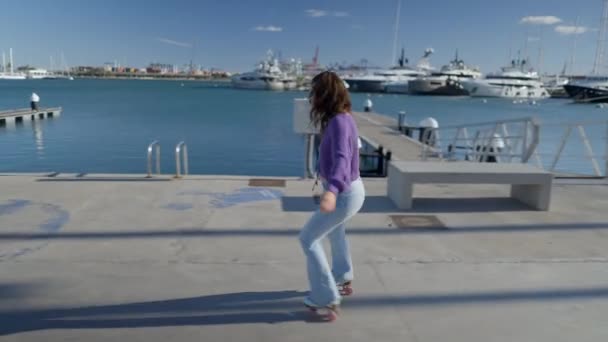 Young Woman Roller Skates Backwards Boats Harbor Sunlight Horizontal Video — Stockvideo
