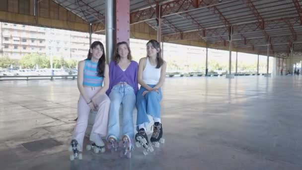Three Girls Wearing Roller Skates Sit Talk Laugh Handheld Horizontal — Stockvideo