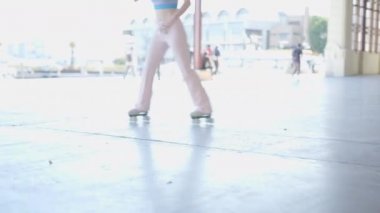 Young dark-haired woman roller skates outdoors, tilt up from floor - 4K Horizontal video