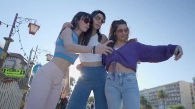 Girls in sunglasses and colorful clothes take selfies with phones - 4K Horizontal video
