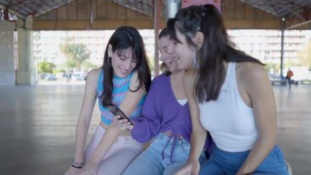 Three Dark Haired Teenage Girls Sit Look Phone Laugh Outdoors — Vídeo de stock