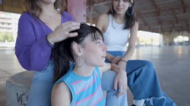 Close view of young women sitting, talking and fixing hair outdoors - 4K Horizontal video