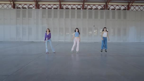 Drie Jonge Vrouwen Rolschaatsen Naar Camera Terwijl Één Voet Vasthouden — Stockvideo