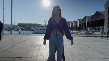 Slomo of three girls roller skating while holding each other by harbor - 4K Horizontal video