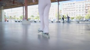 Ground view shot following legs of girl in pink pants roller skating - 4K Horizontal video