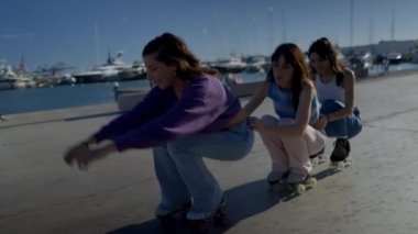 Limanda üç mutlu kız paten kayıyor ve düşüyor, slomo - 4K Yatay Video