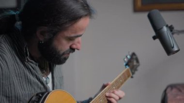 Genç sakallı müzisyen çevrimiçi izleyicilere akor çalıyor.