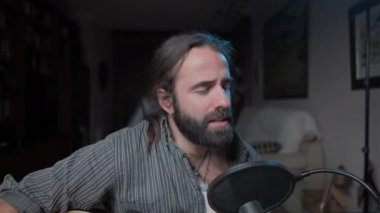 Genç ve çekici bir müzisyen, stüdyosunda duygusal ve mutlu bir şarkı çalıyor.