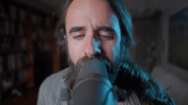 Young bearded man singing an emotional song with professional lightning - Close up shot