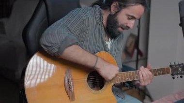 Young influencer guitarist explaining to his online audience the theory of how to play a guitar - Middle shot