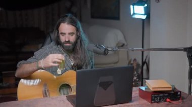 Musician preparing a glass of warm tea and drinking it whilst singing online to take care of his throat - Middle shot