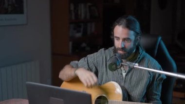 Gimbal shot of a Music Youtuber broadcasting online from his home studio - Middle shot